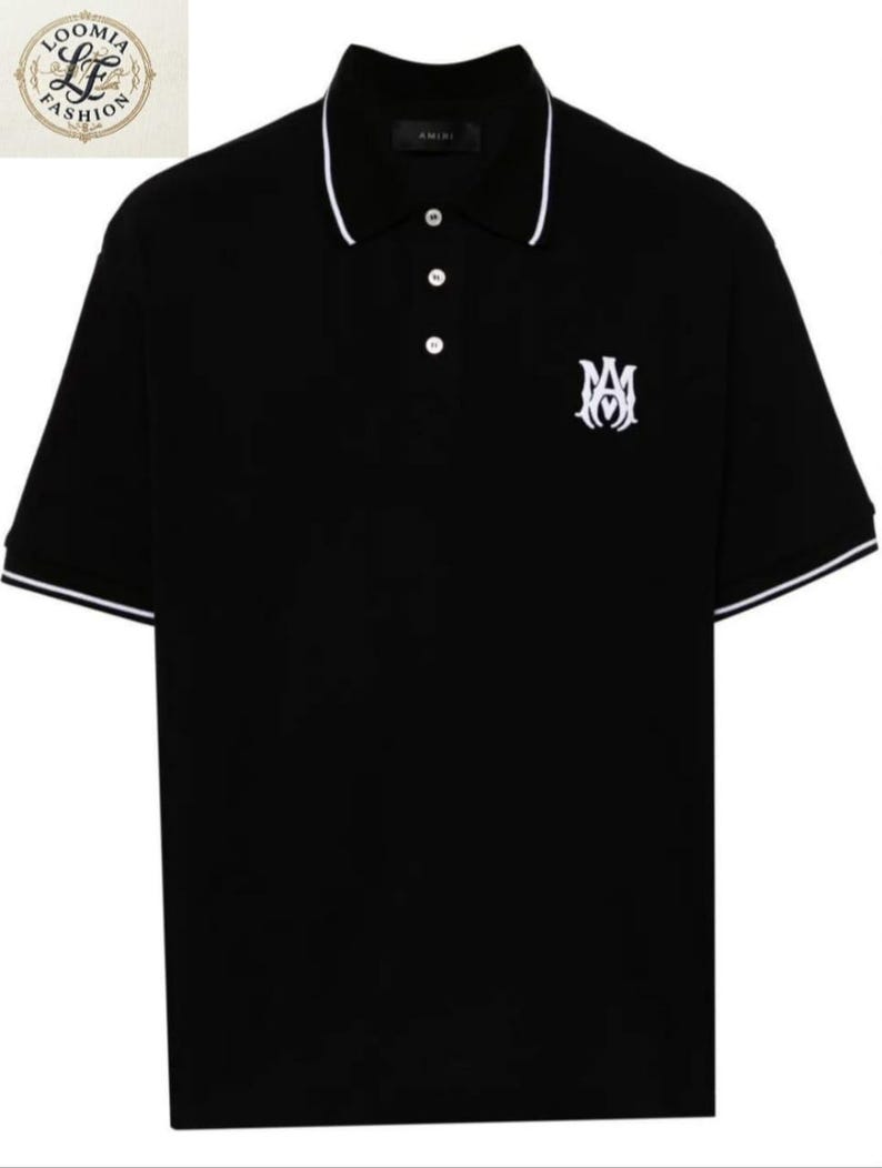 May include: Black polo shirt with white trim on the collar and sleeves. The shirt features a white embroidered logo on the chest and a three-button placket. The brand name "AMIRI" is visible on the collar.
