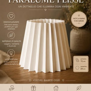 Può includere: Un paralume plissettato bianco con finitura color bianco osso. Il paralume presenta una forma conica con pieghe verticali. Il testo sull'immagine include "PARALUME PLISSÉ", "FATTO A MANO CON CURA", "ALTEZZA 15 cm" e "DIAMETRO 20 cm".