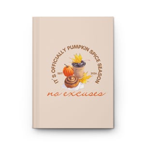 Könnte beinhalten: Ein hellbeiges Notizbuch mit festem Einband und einem zentralen Motiv aus einem Kaffeebecher, einem Kürbis, einer Zimtschnecke und gelben Herbstblättern. Der Text lautet IT'S OFFICIALLY PUMPKIN SPICE SEASON, SEIT 2026 und no excuses in Braun.