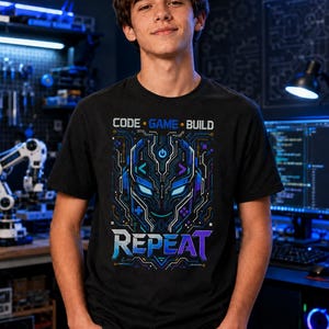 May include: A black short-sleeved t-shirt featuring a graphic print of a stylised robotic face with circuit board patterns in blue, purple, and white. The text reads CODE, GAME, BUILD, and REPEAT in a modern, bold, sans-serif font style.