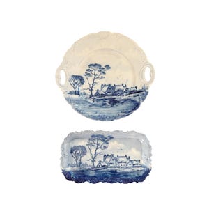 May include: A two-piece set of blue and white porcelain serving dishes. The top dish is round with handles and a scalloped edge. The bottom dish is rectangular with a scalloped edge. Both dishes feature a landscape scene.