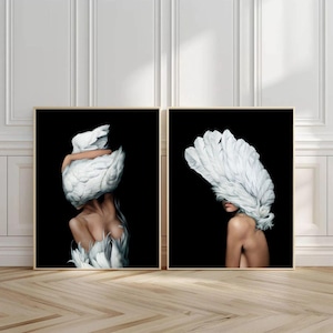 Peut inclure: Deux impressions d'art encadrées. Chaque impression représente le torse et la tête d'une femme, ornés de plumes blanches sur fond noir. L'œuvre a un style surréaliste et artistique. Les cadres sont de couleur marron clair.