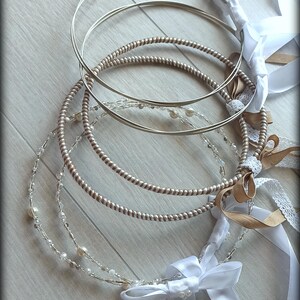 May include: A collection of wedding crowns with silver and gold tones. The crowns are adorned with pearls, ribbons, and bows. The design includes a twisted metal band and a delicate beaded strand.