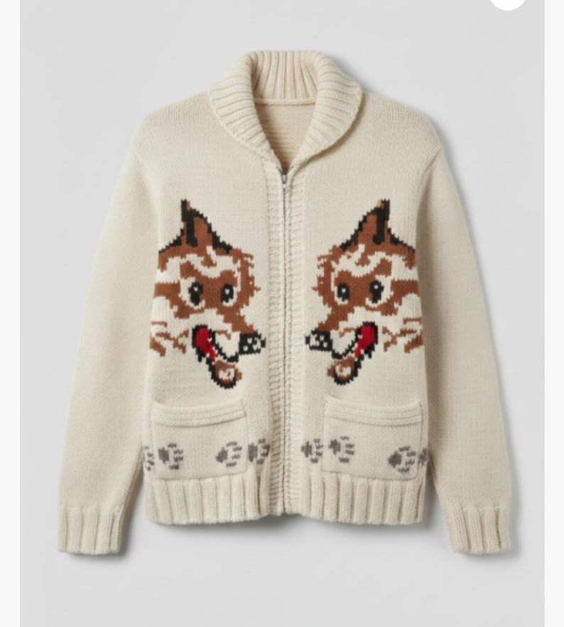 May include: Cream-colored zip-up cardigan sweater with a shawl collar and two front pockets. The sweater features a repeating pattern of two cartoon fox faces in brown, white, and red. The sweater is made of a knitted material.