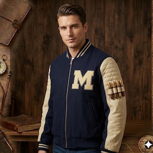 Puede incluir: Chaqueta universitaria azul marino con mangas acolchadas color crema y una gran letra "M" en el pecho. La chaqueta tiene cremallera frontal y un pequeño bolsillo en la manga. Estilo clásico.