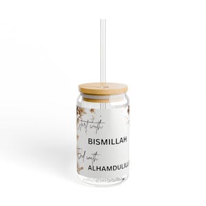 Puede incluir: Un vaso de vidrio transparente con tapa de bambú y pajita transparente. El vaso presenta el texto "Start with Bismillah, End with Alhamdulillah" en escritura negra. Se ven detalles florales en el cristal.