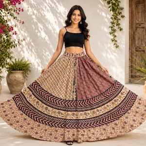 May include: A black sleeveless crop top paired with a long, flared skirt featuring a patchwork design. The skirt displays alternating panels of beige with small floral prints and deep red with intricate patterns, accented by horizontal bands.