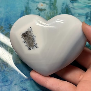 May include: A set of three ceramic mugs with a speckled, matte finish. The mugs are in shades of cream, light gray, and dark gray. Each mug has a simple, minimalist design and a rounded handle.