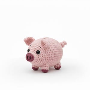 Puede incluir: Un cerdito hucha de ganchillo rosa claro hecho a mano. El cerdo tiene detalles en rosa oscuro en el hocico, las patas y las orejas. Tiene ojos negros y una ranura para monedas en la espalda. Un objeto decorativo caprichoso.