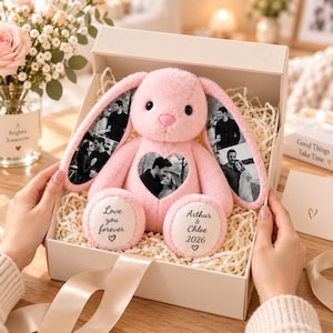 Può includere: Un coniglio di peluche rosa con lunghe orecchie decorate con fotografie in bianco e nero. Il coniglio presenta una foto a forma di cuore sul petto e testo sui piedi con la scritta Love you forever e Arthur & Chloe 2026, in una scatola regalo.