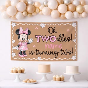 Puede incluir: Una pancarta marr&oacute;n con el texto "Oh TWOodles! name is turning two!" presenta al personaje de dibujos animados Minnie Mouse con un vestido rosa. La pancarta est&aacute; decorada con flores blancas. La escena incluye pasteles, cupcakes y globos.