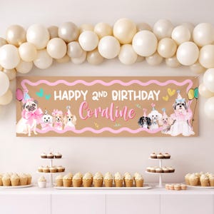 Pode incluir: Uma faixa de aniversário castanha com o texto "Happy 2nd Birthday Coraline" e ilustrações de cães com chapéus de festa e laços. A faixa tem detalhes em rosa e é decorada com balões. Cupcakes e balões também são visíveis.