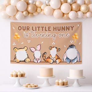 Puede incluir: Una pancarta de fiesta rectangular de color tostado con el texto "OUR LITTLE HUNNY is turning one" en marrón y blanco. Debajo del texto hay cuatro ilustraciones de animales de dibujos animados con caras blancas vacías sobre una mesa.