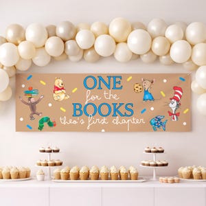 May include: A brown banner with the text "ONE for the BOOKS theo's first chapter" and cartoon characters. The banner is decorated with balloons and cupcakes, suggesting a book-themed party.