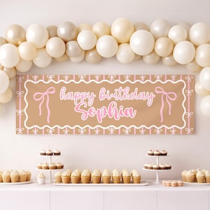Puede incluir: Una pancarta de cumpleaños rectangular de color tostado con un borde festoneado blanco, rayas verticales rosas e ilustraciones de lazos rosas. El texto "happy birthday Sophia" aparece en letra cursiva blanca bajo un arco de globos color crema.