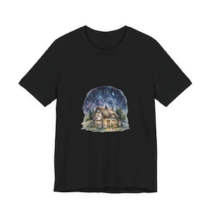 Peut inclure: Un t-shirt noir à manches courtes avec une illustration graphique centrée représentant un petit cottage au toit de chaume sous un ciel nocturne bleu foncé rempli d'étoiles, d'un croissant de lune et de traînées lumineuses, entouré d'arbres verts.