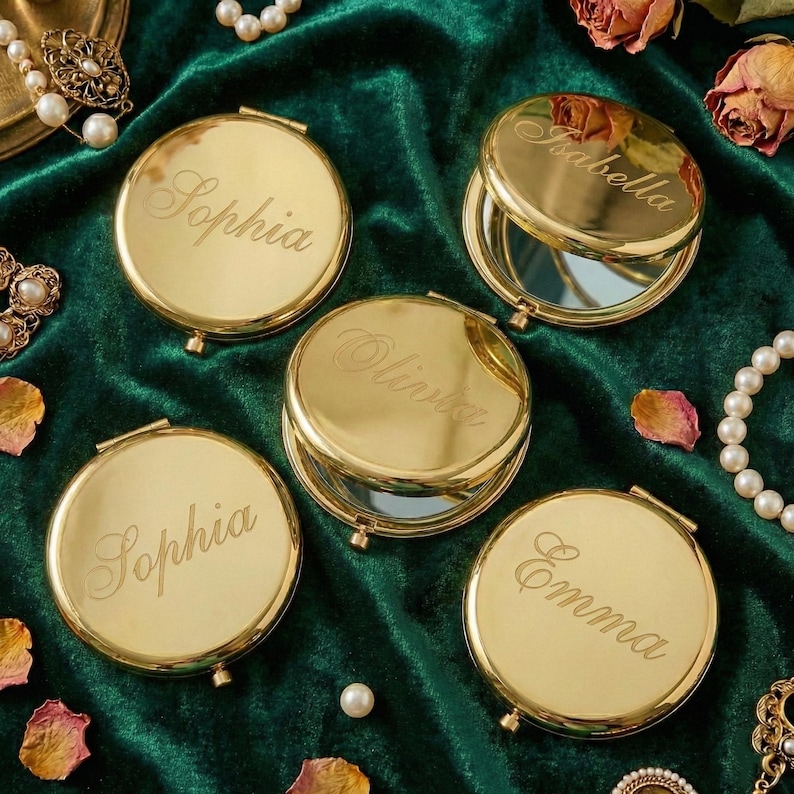 Peut inclure: Miroirs compacts dor&eacute;s avec les noms grav&eacute;s Sophia, Olivia, Emma et Isabella. Les compacts ronds s'ouvrent pour r&eacute;v&eacute;ler un miroir. Le fond est un tissu de velours vert fonc&eacute; avec des perles et des fleurs s&eacute;ch&eacute;es.
