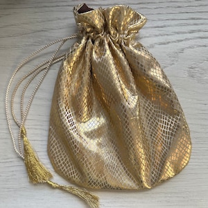 May include: A gold drawstring bag with a snakeskin pattern and a tassel.