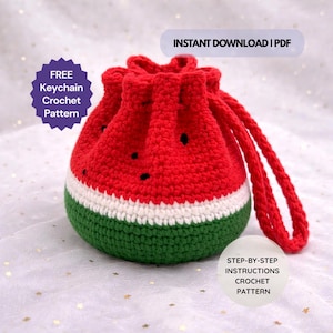 May include: A handmade crochet watermelon-shaped drawstring bag. The bag is red with black seed details, a white stripe, and a green base. It has a red drawstring and the text "INSTANT DOWNLOAD | PDF". Also, the text "FREE Keychain Crochet Pattern" and "STEP-BY-STEP INSTRUCTIONS CROCHET PATTERN".