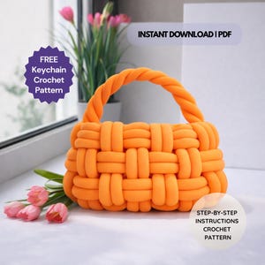 May include: An orange crochet handbag with a woven design and a twisted handle. The image includes text that says "FREE Keychain Crochet Pattern" and "INSTANT DOWNLOAD | PDF". The bag is displayed with pink tulips and other decorative elements.