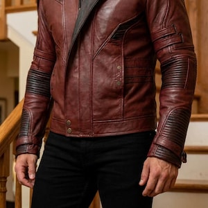 Pu&ograve; includere: Giacca in pelle bordeaux con dettagli neri. La giacca presenta una cerniera asimmetrica, dettagli a coste sulle maniche e diverse tasche. Indossata con pantaloni neri, crea un look moderno ed elegante.