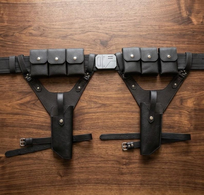 May include: A black utility belt system featuring two holsters, six rectangular pouches with silver snap closures, and a central silver-toned rectangular buckle. The harness includes adjustable straps with metal buckles for secure attachment.