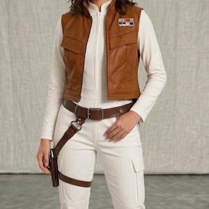 May include: A brown faux leather vest with a high collar and two chest pockets, worn over a white long-sleeve top and white cargo pants. A brown leather belt with an attached holster is worn around the waist and thigh, featuring a metallic buckle.