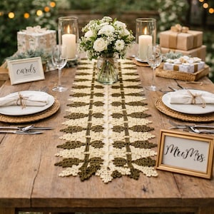 May include: A beautifully set table with a cream and olive green crochet table runner. The table is decorated with white flowers, candles, and framed signs that read "cards" and "Mr & Mrs".