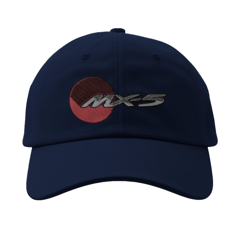 May include: Navy blue baseball cap featuring the embroidered text "MX-5" in silver, with a red and maroon circular design on the front. The cap has a curved brim and a structured crown, suitable for sun protection.