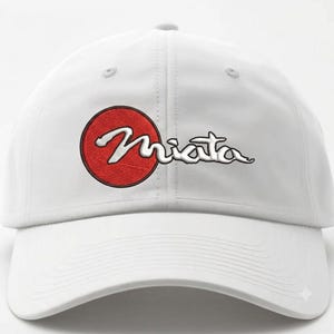 May include: A white baseball cap featuring an embroidered design on the front. The design consists of a solid red circle with the word Miata written in white cursive script across it. The cap has a curved brim and a structured six-panel crown.