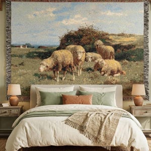May include: A woven tapestry showing sheep in a field under a blue sky, displayed above a bed with neutral bedding and decorative pillows. The room features matching bedside tables and lamps. The tapestry is a decorative wall hanging.