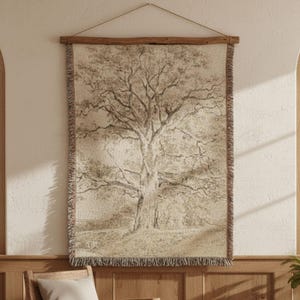 May include: A sepia-toned woven tapestry depicting a large tree, hung on a wall. The artwork is framed by a wooden rod and a fringed border. The tapestry is displayed on a light-coloured wall, creating a rustic aesthetic.