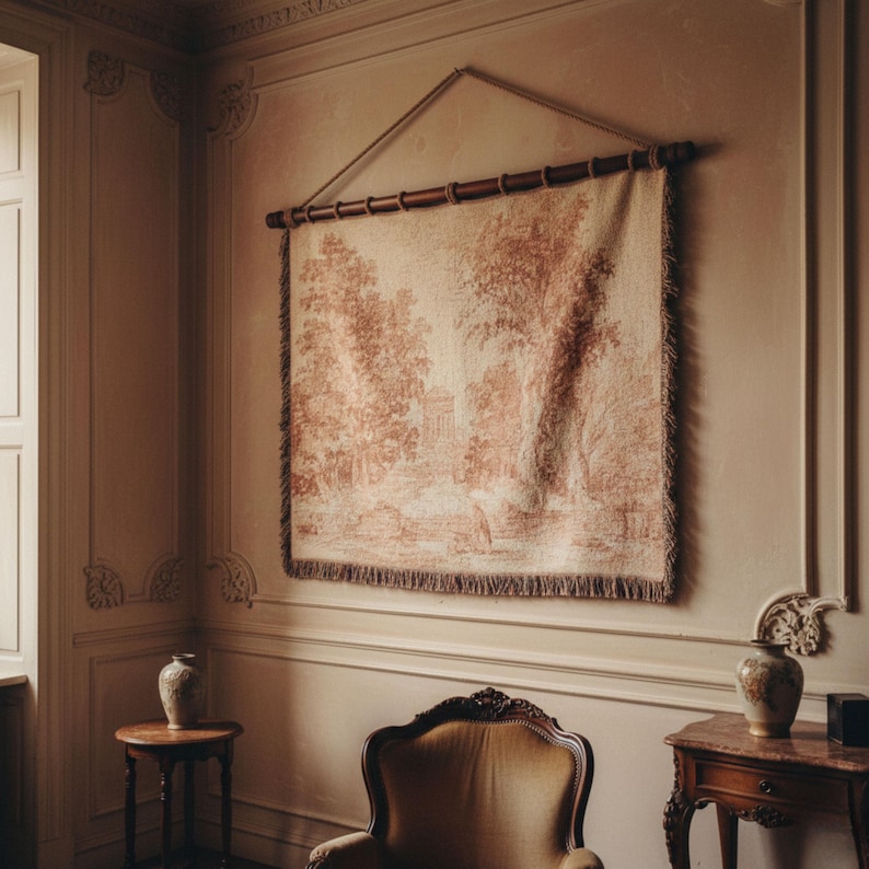 May include: A tapestry depicting a landscape scene in shades of red and cream, hanging from a wooden rod and rope. The tapestry features a detailed illustration of trees, buildings, and figures. The edges are finished with a fringed border, adding a touch of texture.
