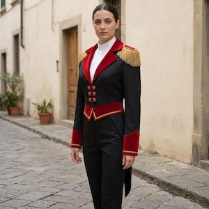 May include: A black military-style jacket with red velvet accents on the collar, cuffs, and waist. The jacket features gold fringe epaulets and decorative buttons. The matching black pants complete the ensemble, creating a striking, formal look.