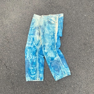 Op de afbeelding: Lichtblauwe spijkerbroek met een all-over print van luipaardgezichten en vlekken. De broek heeft een klassiek ontwerp met vijf zakken, een knoopsluiting, riemlussen en rechte broekspijpen met een vervaagde, gewassen uitstraling.