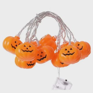 May include: A string of orange pumpkin-shaped lights with black carved faces. The lights are strung on a silver wire and connected to a small battery pack. Ideal for Halloween decorations.