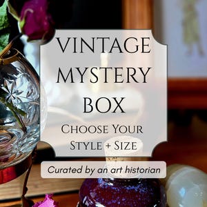 May include: Image of a vintage mystery box with text that reads "Vintage Mystery Box, Choose Your Style + Size, Curated by an art historian." The image includes a purple bottle, a clear glass, and a white stone.