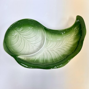 May include: A ceramic serving dish shaped like a large leaf with a divided interior. The dish features a gradient color scheme, transitioning from a deep forest green at the outer edges to a lighter, pale white center, with embossed leaf veins.