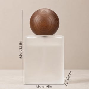 May include: A rectangular frosted glass perfume bottle with a round dark brown wooden cap. The bottle measures 3.62 inches in height, 1.93 inches in width, and 0.99 inches in depth, as indicated by the visible measurement lines and text.