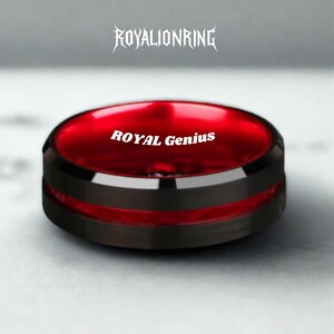 Op de afbeelding: Een zwarte ring met een rode kern en de tekst "ROYAL Genius" in het wit. De ring heeft een zwarte band met een rode streep. De tekst "ROYALIONRING" staat boven de ring.