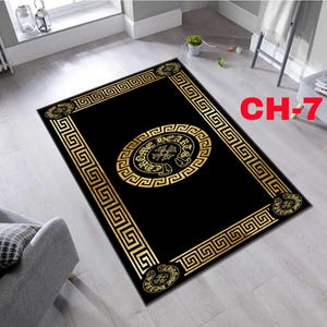 Puede incluir: Una alfombra rectangular negra con un borde dorado de patrón de grecas y un emblema circular central con el texto CHROME HEARTS. Las cuatro esquinas muestran motivos circulares con el mismo texto. La alfombra está etiquetada como CH-7.