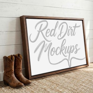 Könnte beinhalten: Gerahmtes Leinwand-Mockup mit dem Text "Red Dirt Mockups" in Schreibschrift. Der Rahmen ist dunkelbraun und die Leinwand ist weiß. Zwei braune Cowboy-Stiefel stehen vor dem Rahmen und liegen auf einem gewebten Teppich.