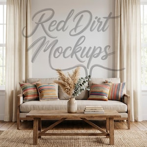 May include: A living room scene featuring a beige sofa with colorful striped pillows, a wooden coffee table, and a vase with dried plants. The wall has the text "Red Dirt Mockups" in a script font. Beige curtains frame the windows.