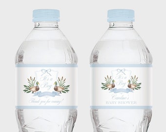 May include: Two clear plastic water bottles with light blue caps. Each bottle has a label with the text "It's a Boy" above a banner that says "Thank you for coming!" and a watercolor illustration of ducks and reeds. Baby shower theme.