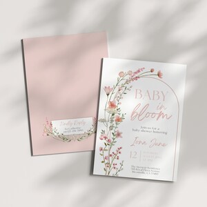 May include: A pink baby shower invitation with a floral wreath and the text "Baby in Bloom" and "Join us for a baby shower honoring [name] [date] [time] [location]"