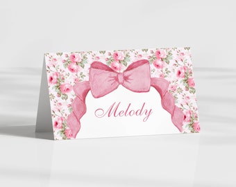 May include: Pink floral place card with a pink bow and the name "Melody" printed in cursive.