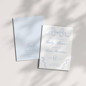 May include: A white baby shower invitation with blue ribbon designs. The invitation reads "Please join us for a Baby Shower in honor of Eloise Thornton" with the date and time of the event.