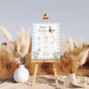 May include: A blue and white gingham poster with a duck illustration and the text "Reid's First Year 22nd April 20XX". The poster lists milestones such as first tooth, first word, and first steps.