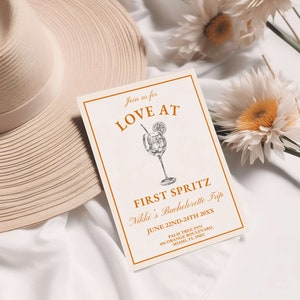 May include: A white card with orange text that reads "Join us for Love At First Spritz Nikki's Bachelorette Trip June 22nd-24th 20XX Palm Tree Inn 456 Orange Boulevard, Miami, FL. 25463". The card has a drawing of a cocktail glass with a lemon slice and a straw.