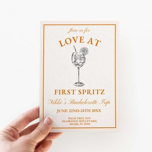 May include: Orange and white invitation for a bachelorette party called "Love at First Spritz". The invitation features a drawing of a glass of a spritzer with a lemon slice and a straw. The text includes the date, June 22nd-24th 20XX, and the location, Palm Tree Inn, 456 Orange Boulevard, Miami, FL 29403.